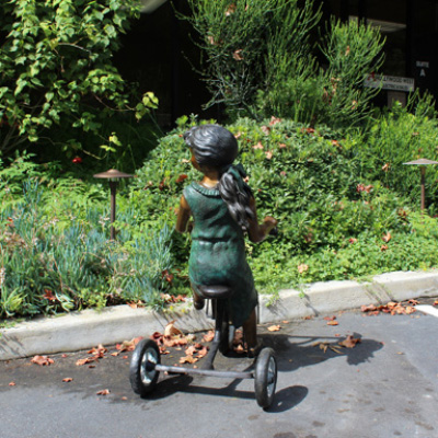 Rear Bronze Girl Riding Tricycle Sculpture outdoors