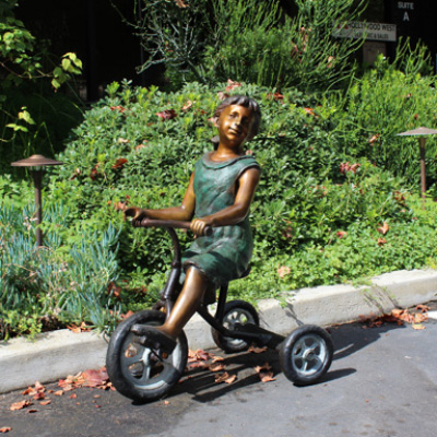 Side view Bronze Girl Riding Tricycle Sculpture