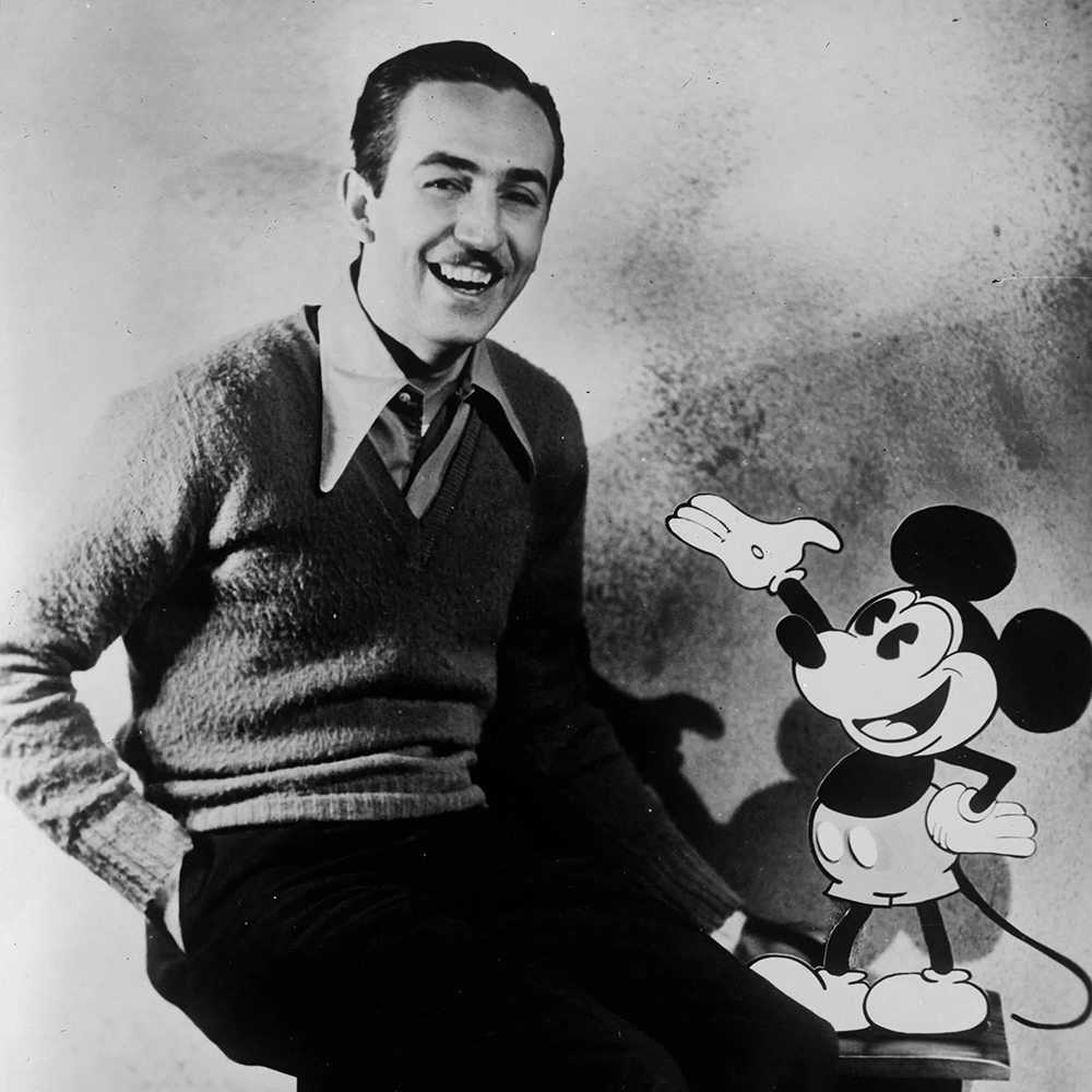 Walt Disney seated beside Mickey Mouse artwork
