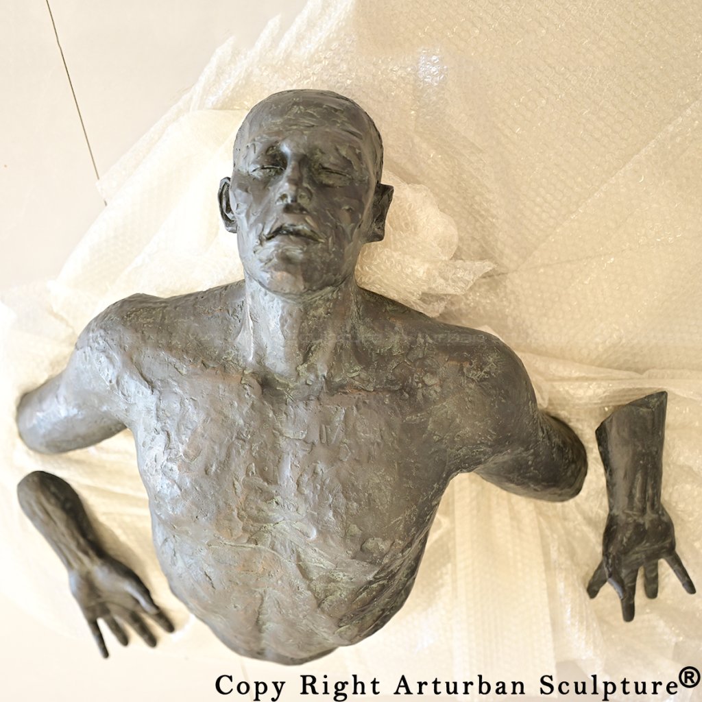 0 Close view of bronzeman breaking through wall sculpture