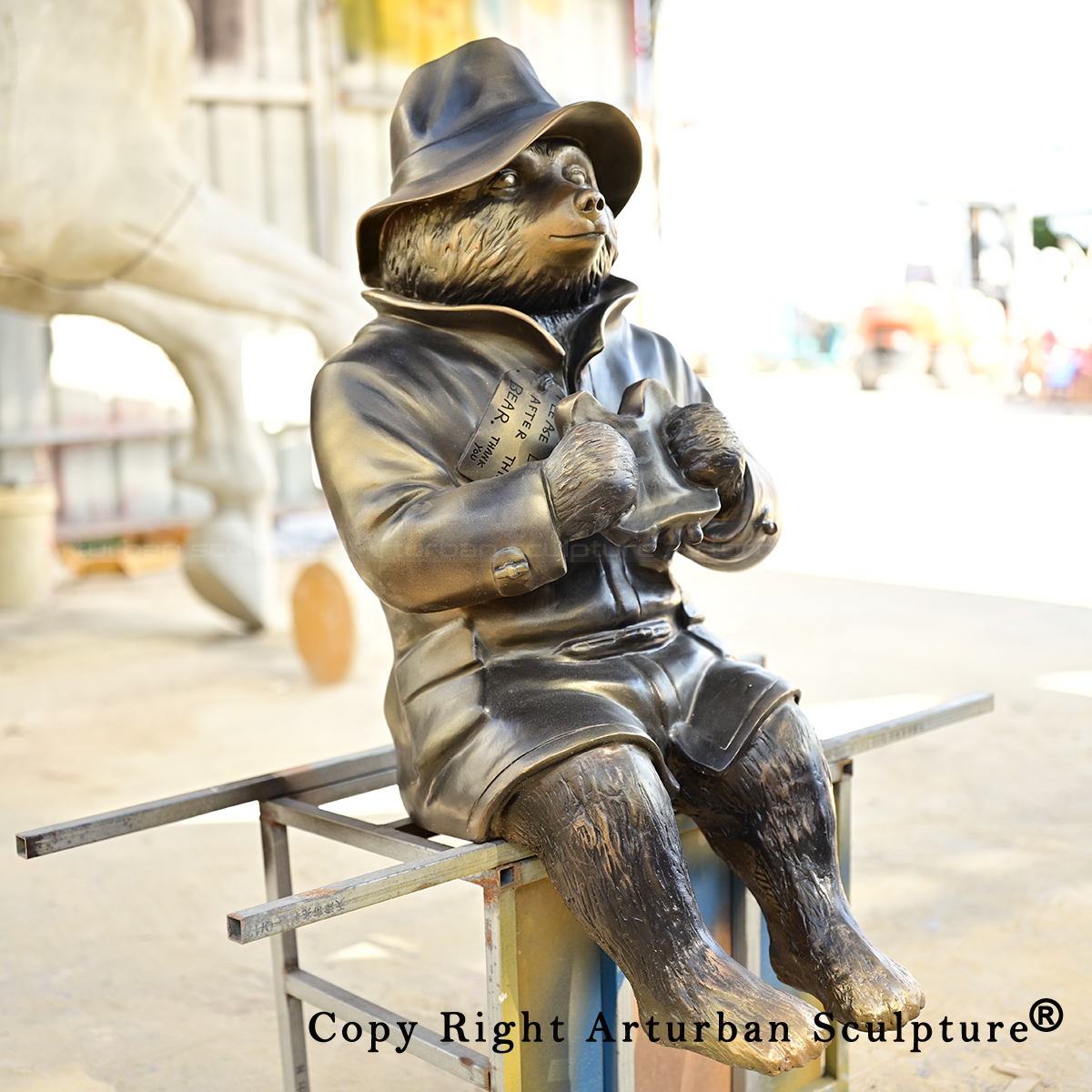 Seated Paddington Bear Garden Statue holding sandwich in coat