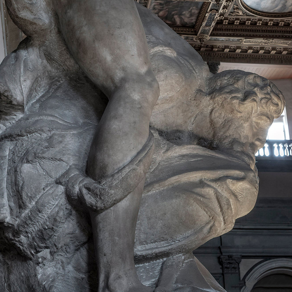 Defeated figure beneath victory statue