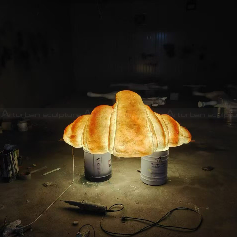 Illuminated fiberglass croissant statue in workshop setting