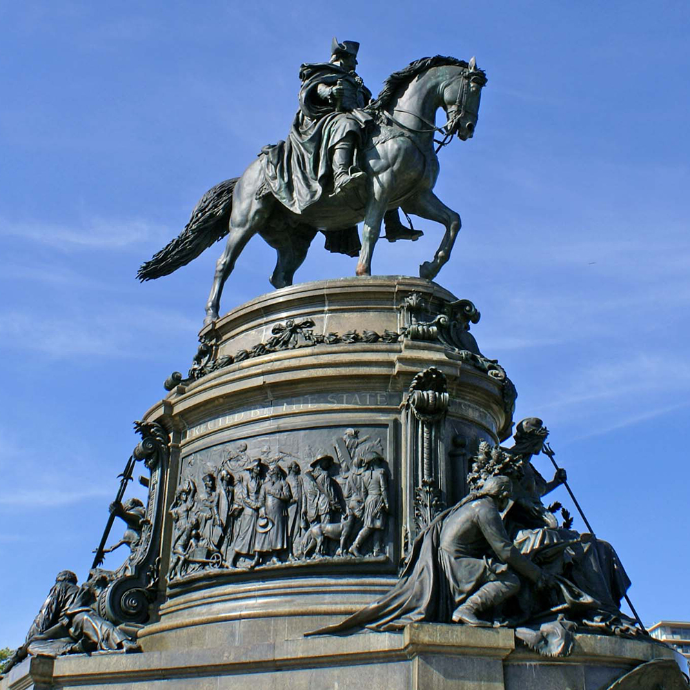 George Washington statue above historical bronze relief