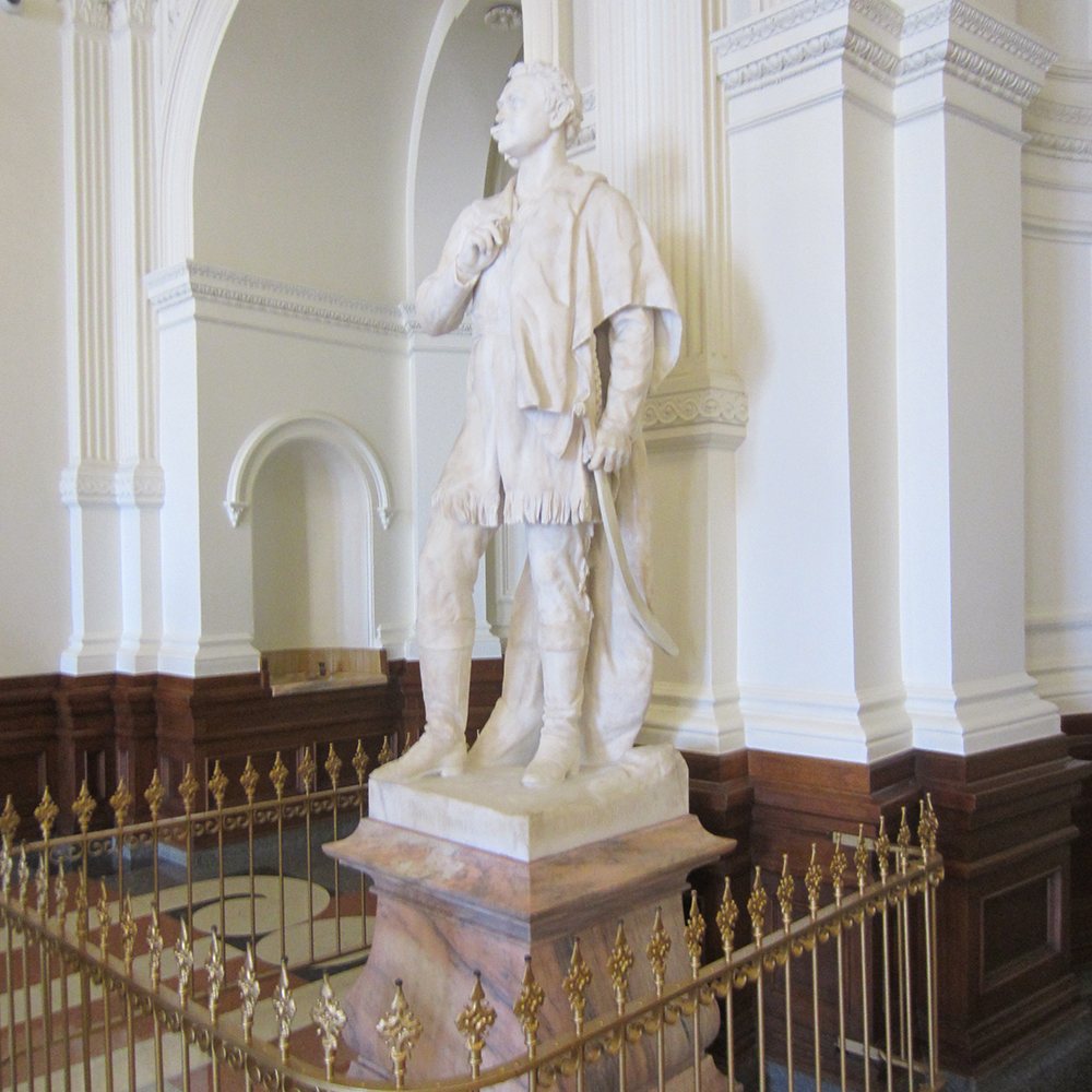 Marble frontier figure beside Texas Capitol columns